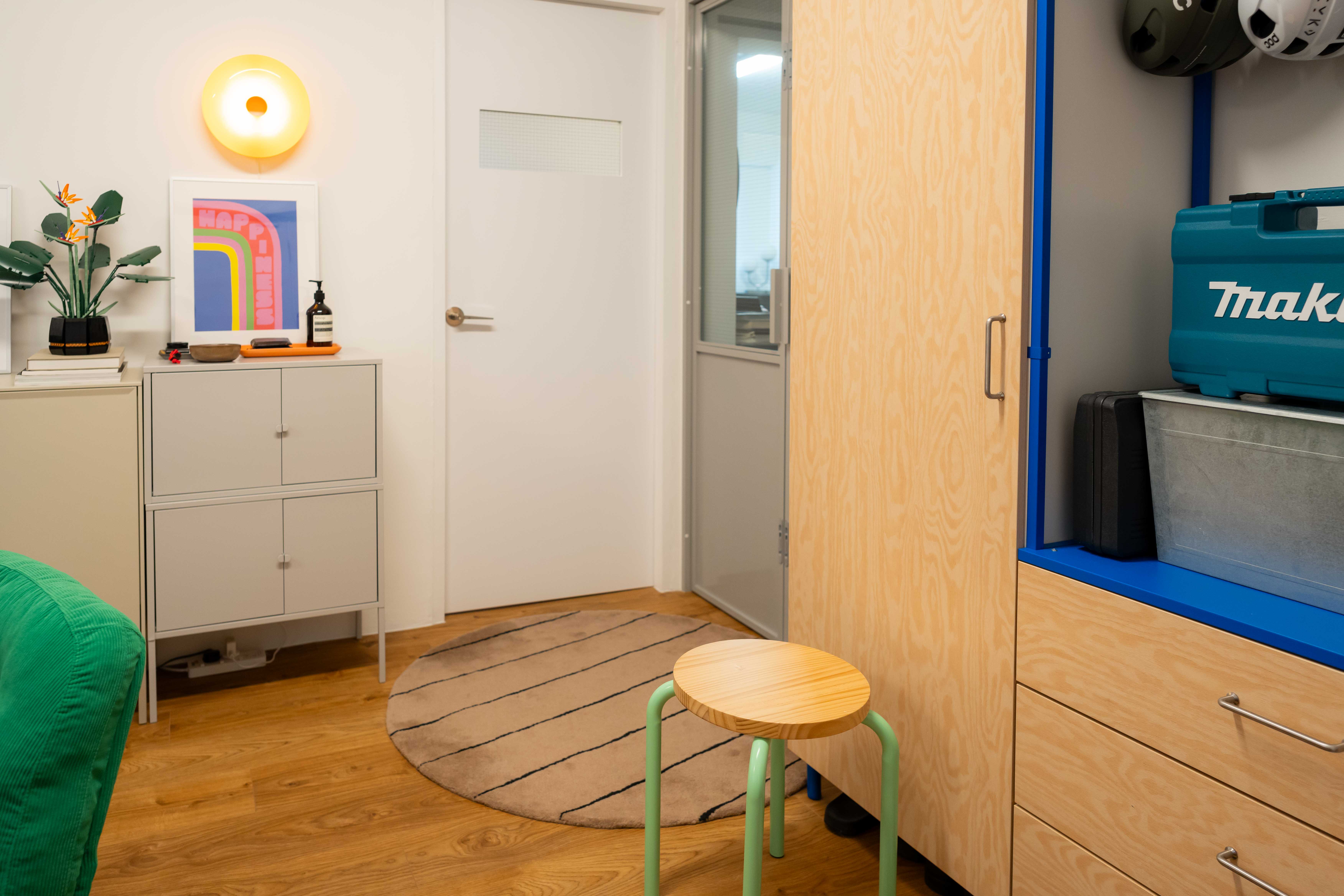 A colourful entryway with vibrant hues and a sporty vibe! - Modern minimalist bedroom, wooden floor, round wooden stool