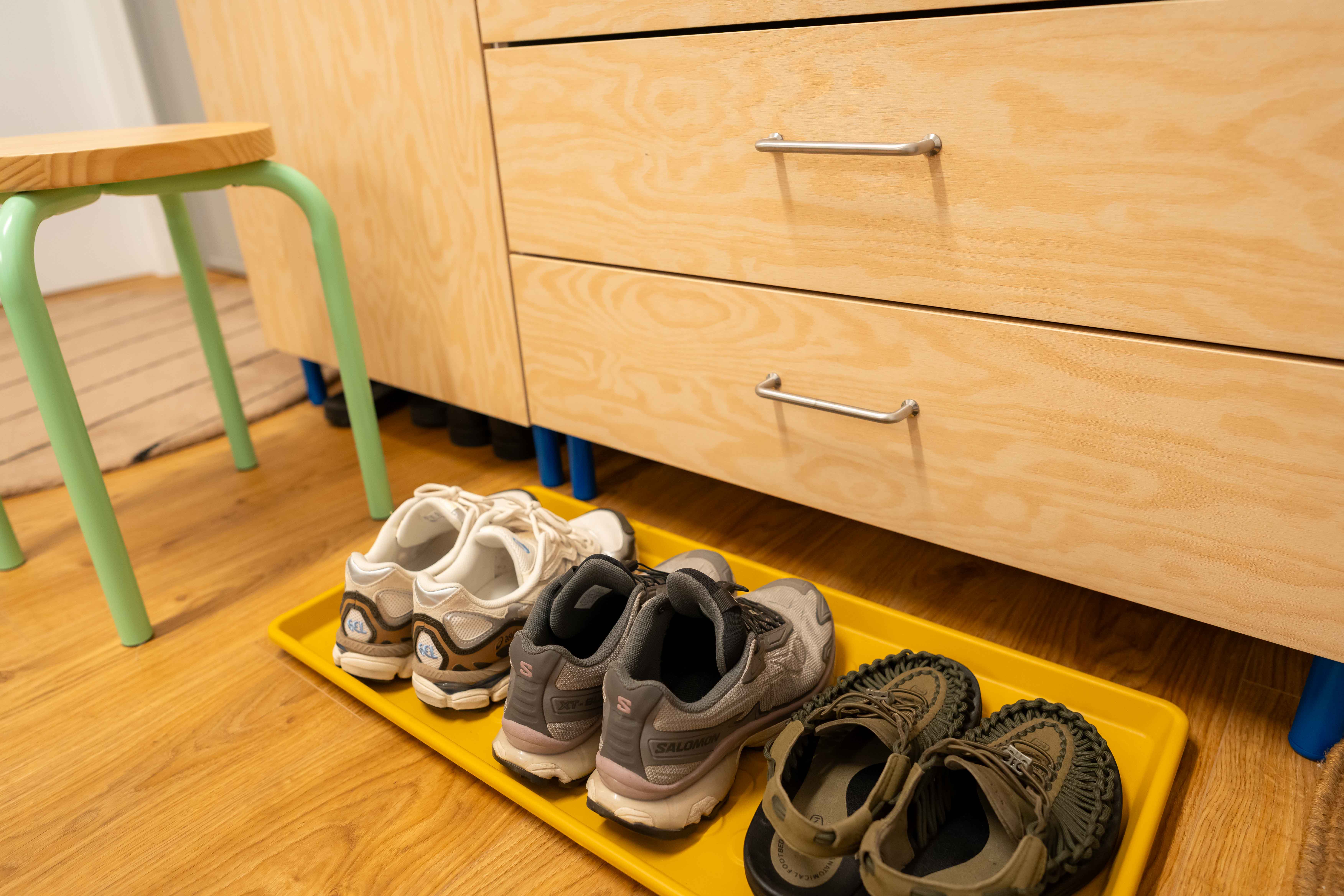 A colourful entryway with vibrant hues and a sporty vibe! - Sneakers, yellow tray, wooden floor, light wooden cabinet, green