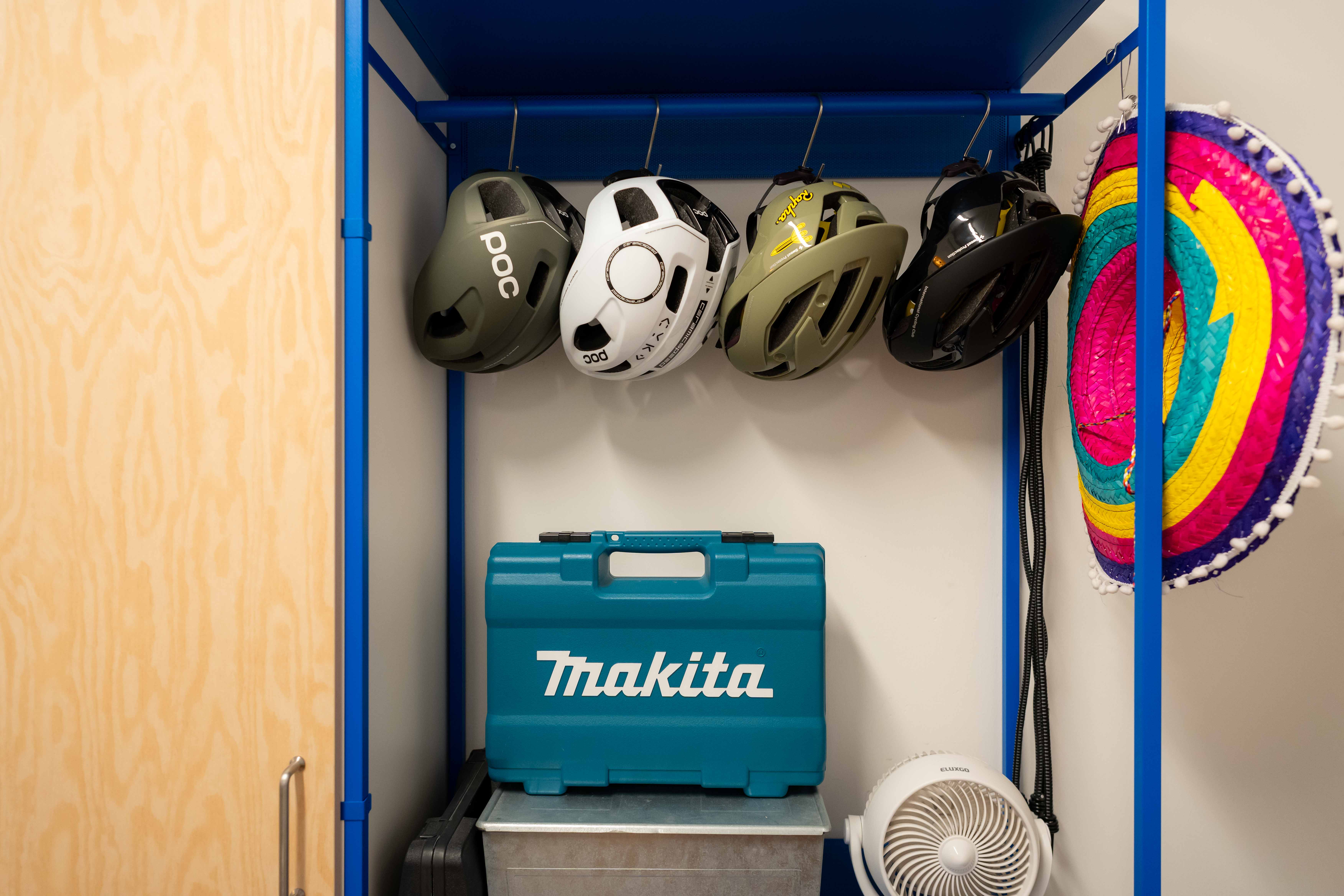 A colourful entryway with vibrant hues and a sporty vibe! - blue storage cabinet, bicycle helmets, colorful helmet, black