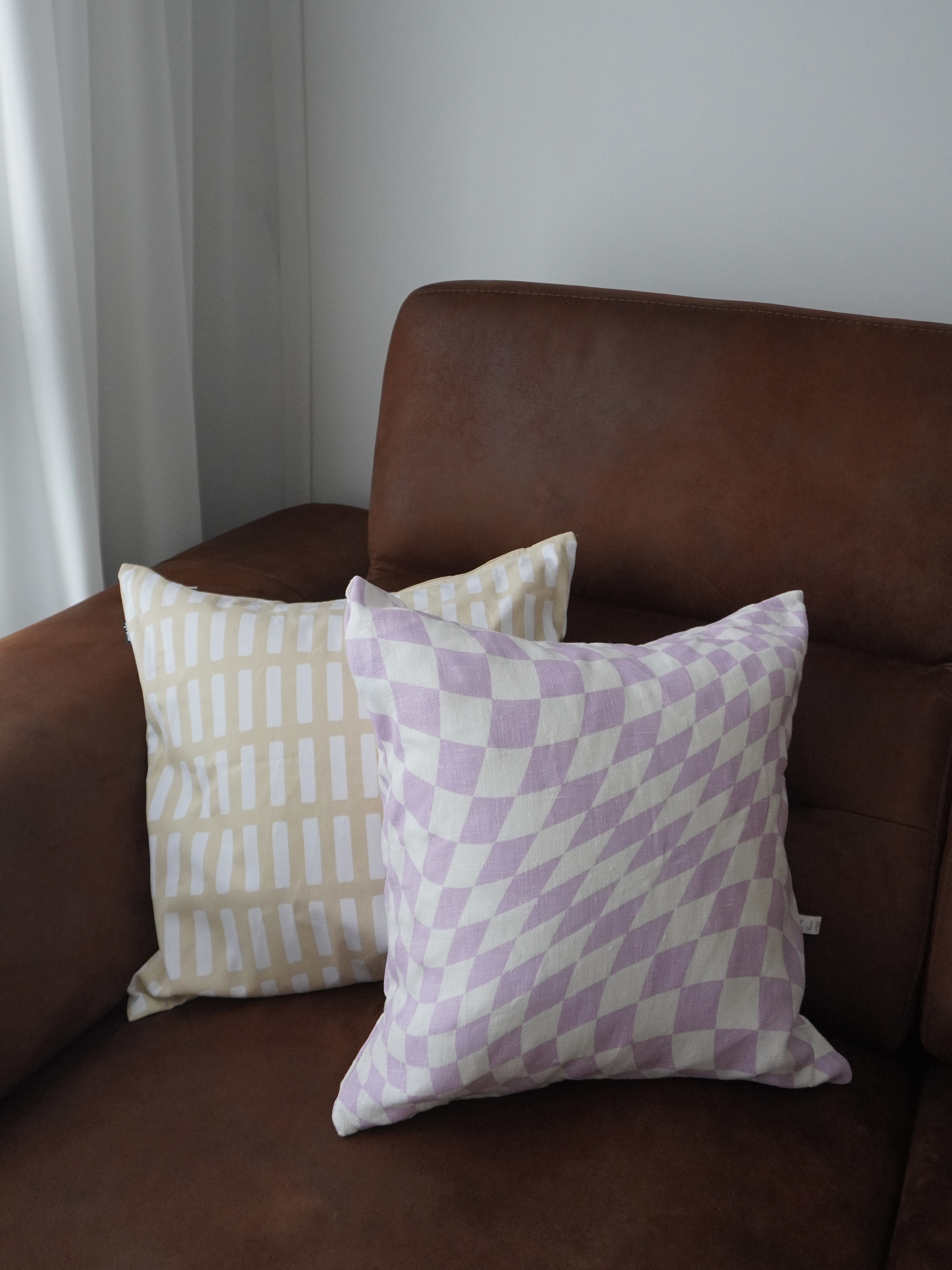 Living Room: 4-Rm BTO with no built-ins  - Brown leather sofa, two pillows, beige and purple checkered, modern design, cozy