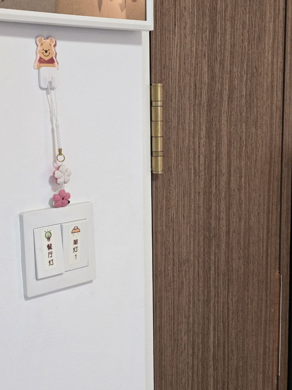 Entryway: Playful Mat Meets Our $1.8K Settee! - Wooden door, white switch, hanging keychain, bear charm, pink flowers, light