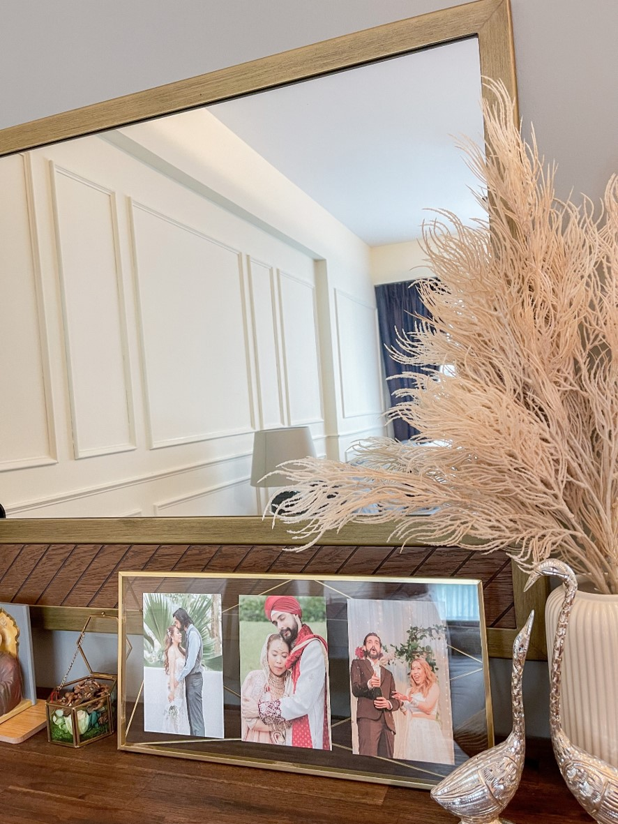 Sleek harmony in our living room - Golden frame, elegant mirror, wedding photos, decorative vase, natural feathers, indoor