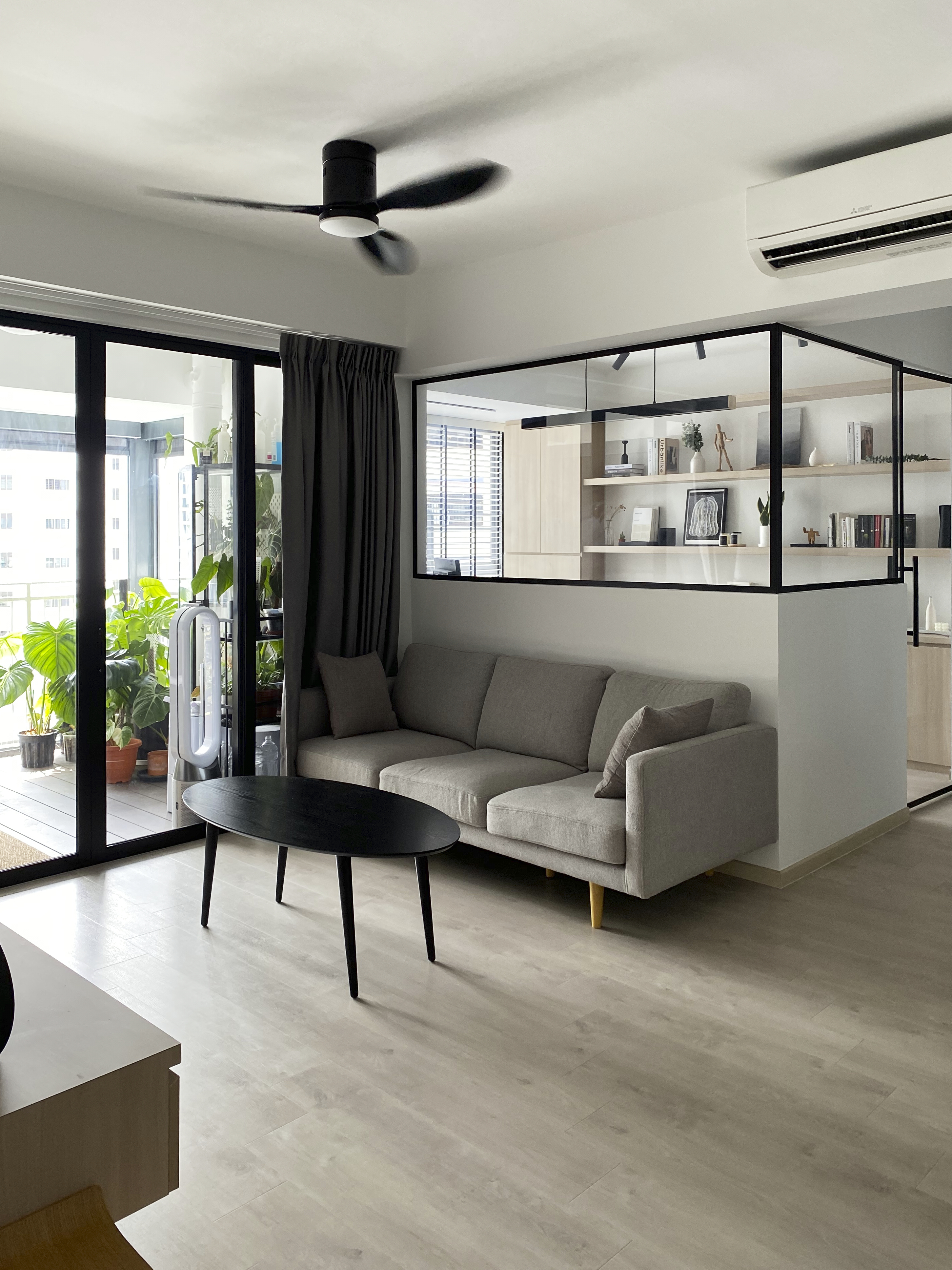 Clean Aesthetics With Grey And Black Hues  - Modern living room with gray sofa, black coffee table, large glass sliding