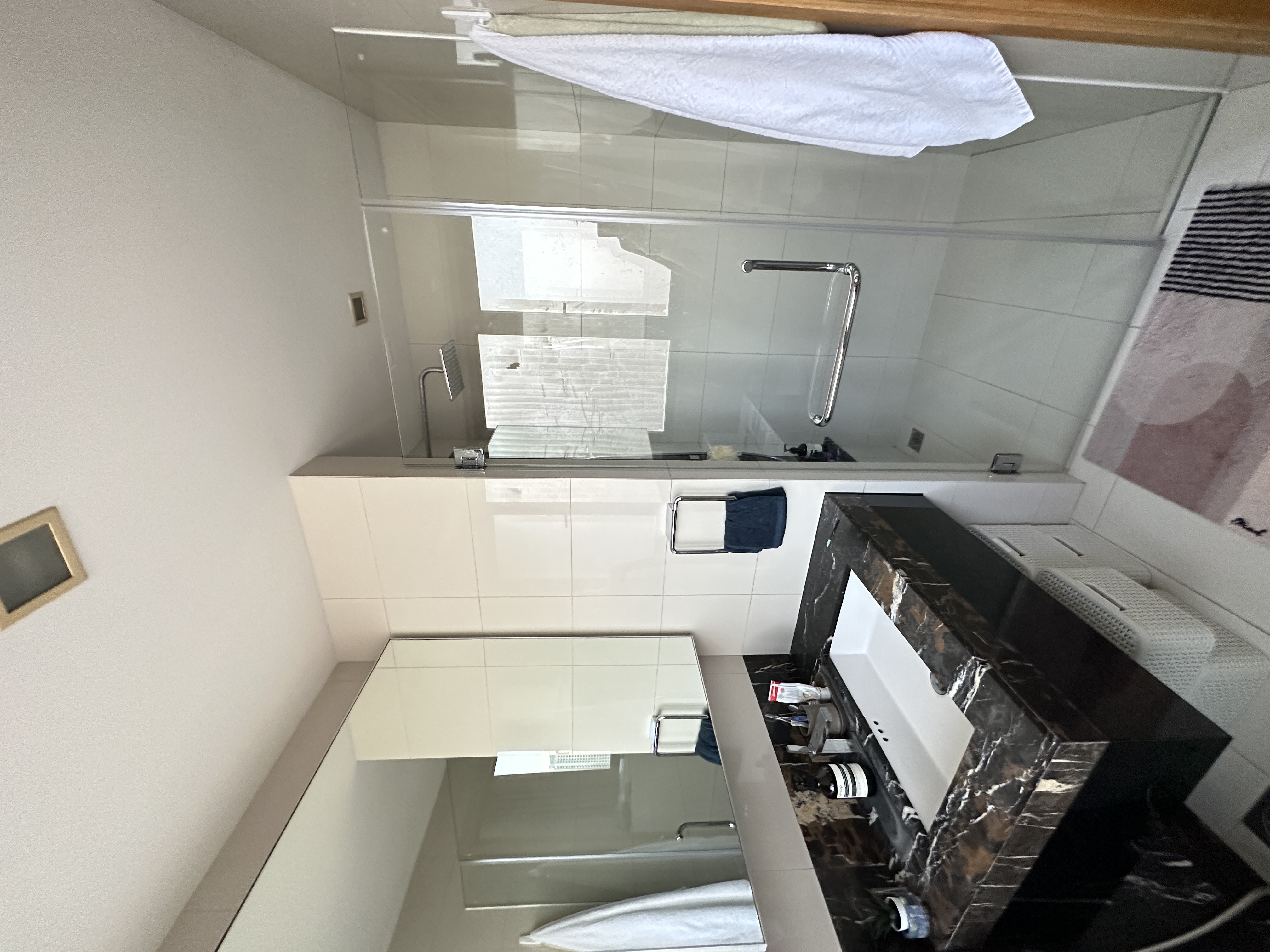 Welcome To Our Mid-Century Modern Condominium - Glass-enclosed shower, white tiles, modern design, white towels, sleek sink