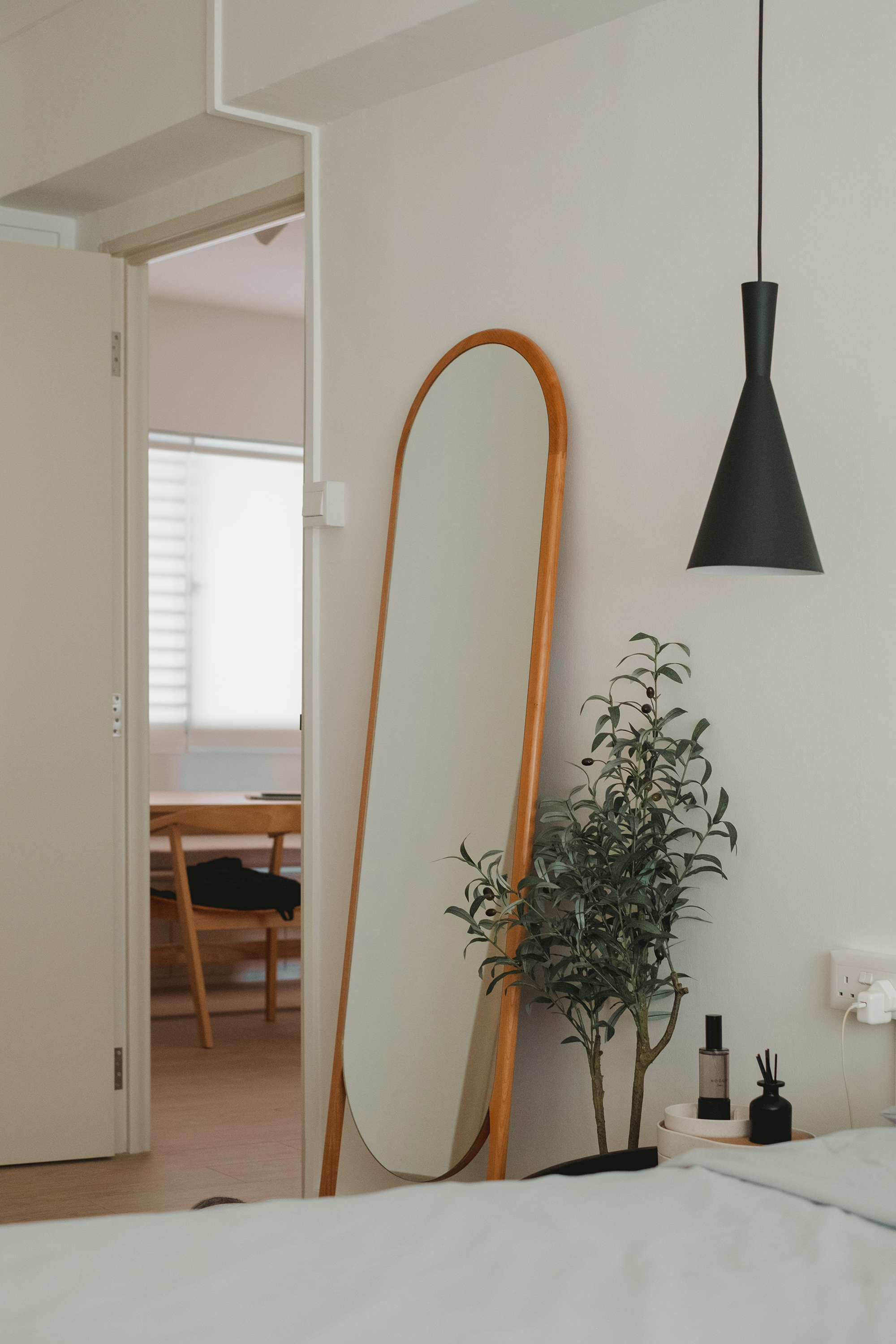 Chic Minimalist Mornings - Modern minimalist bedroom, white walls, wooden door frame, hanging pendant light, green plant