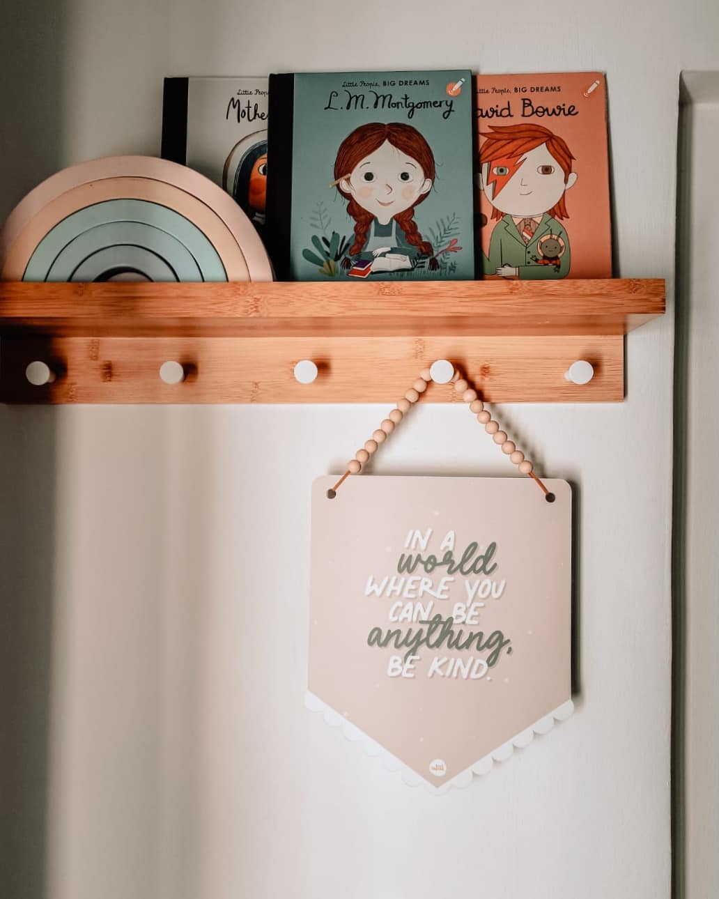 Playful Pink or Neutral Kids Room? - Wooden shelf with children's books and a decorative sign, Illustrative children's book