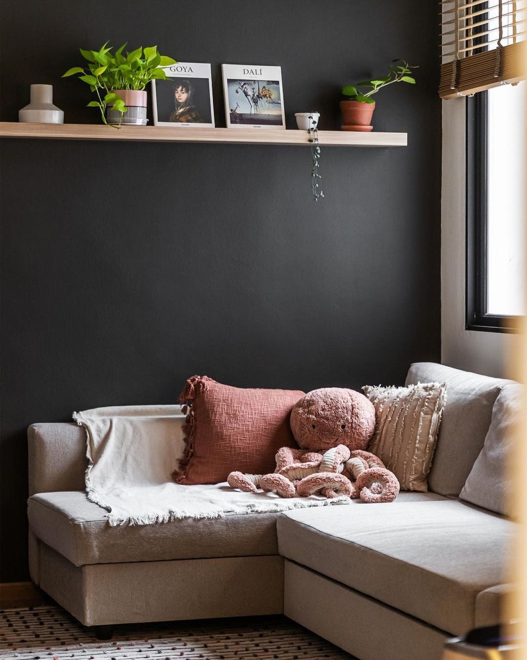Eclectic Cosiness Unveiled - Light-filled room with cozy sofa, soft cushions, and plush teddy bear. Dark gray wall with