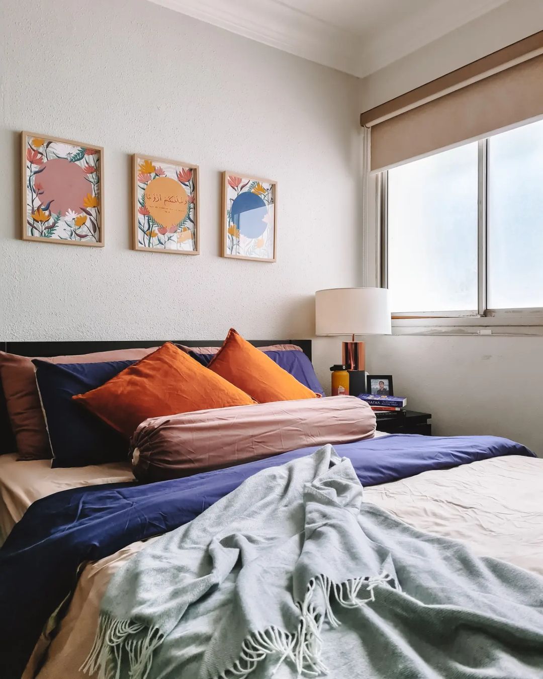 Cosy Colour Pop Bedroom - Floral-themed wall art, vibrant orange and blue pillows, cozy bed with beige and blue bedding