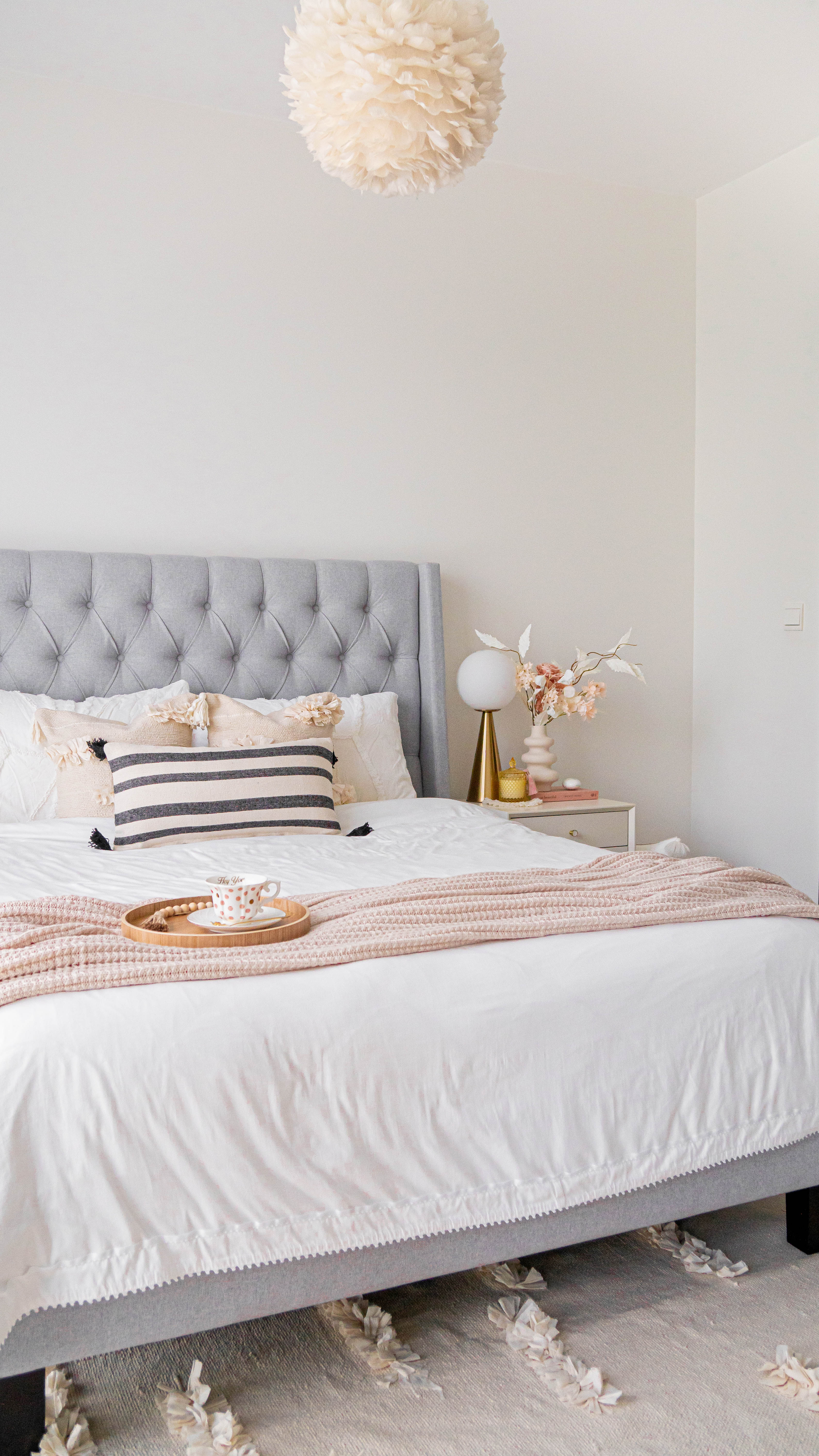 Soft Elegance Dreamland - Cream tufted headboard, white and beige bedding, striped pillows, wooden tray with teacup, pink and