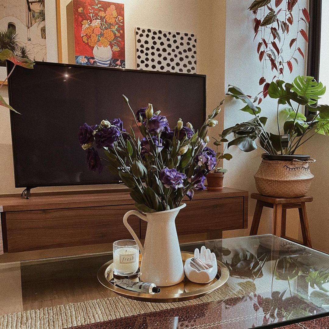 Eclectic Cosiness Unveiled - vibrant purple flowers in white pitcher on glass table, modern living room decor, cozy indoor