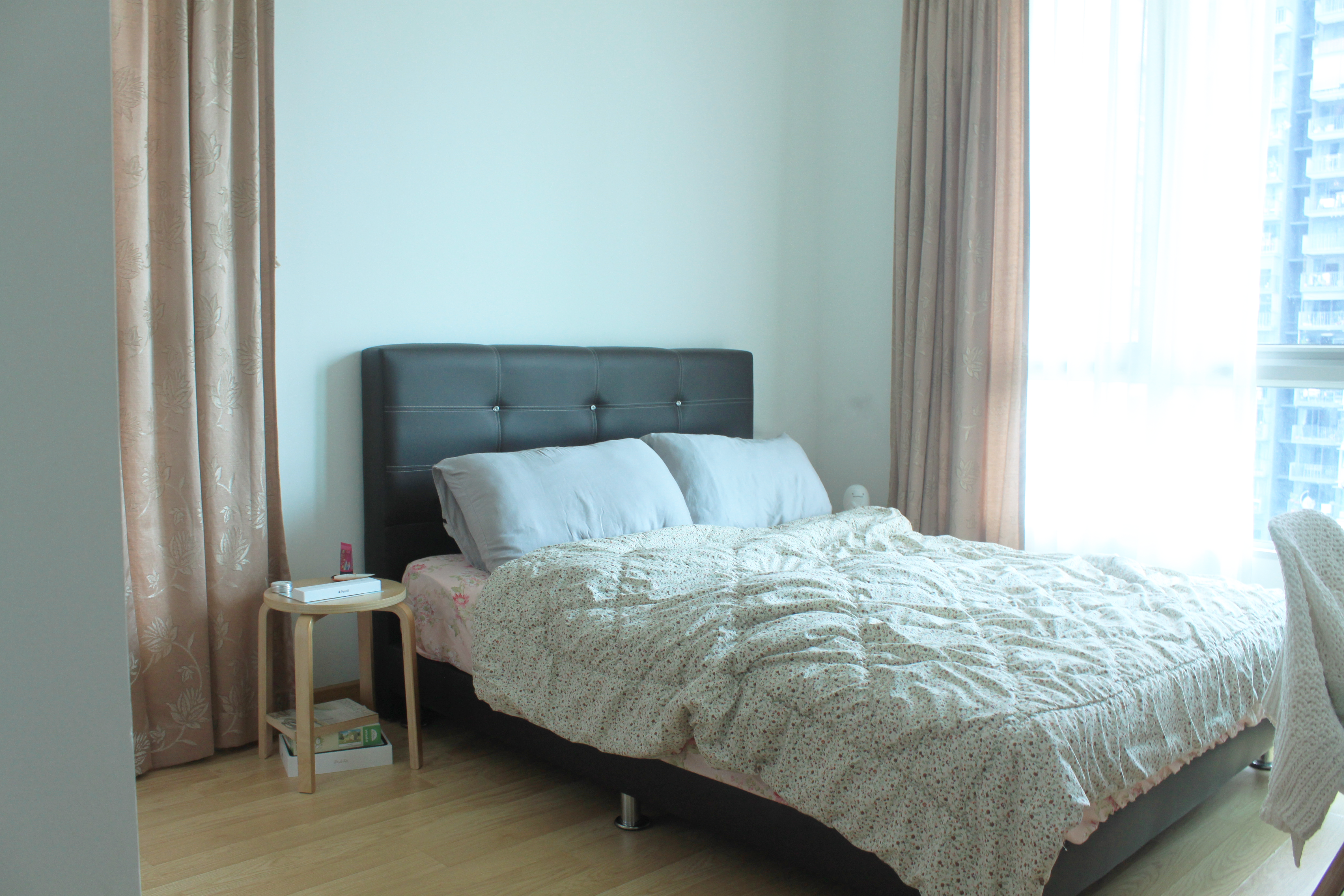 My Home Away From Home - Floral curtains, light blue walls, wooden floor, black headboard, white bedspread, light pink