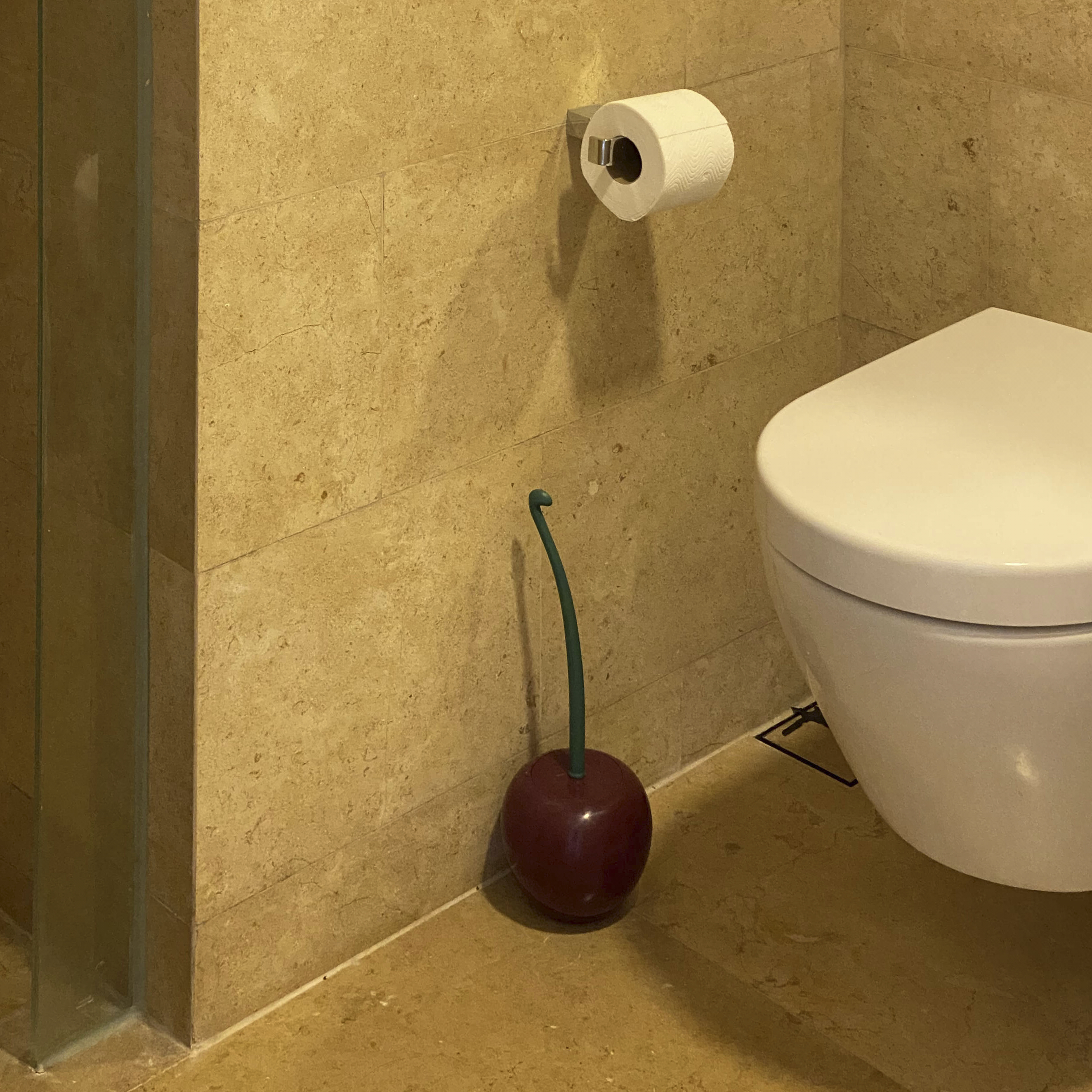 A Photographer's One-Room Studio Man Cave - Toilet paper roll mounted on beige tiled wall, green handle on toilet, white