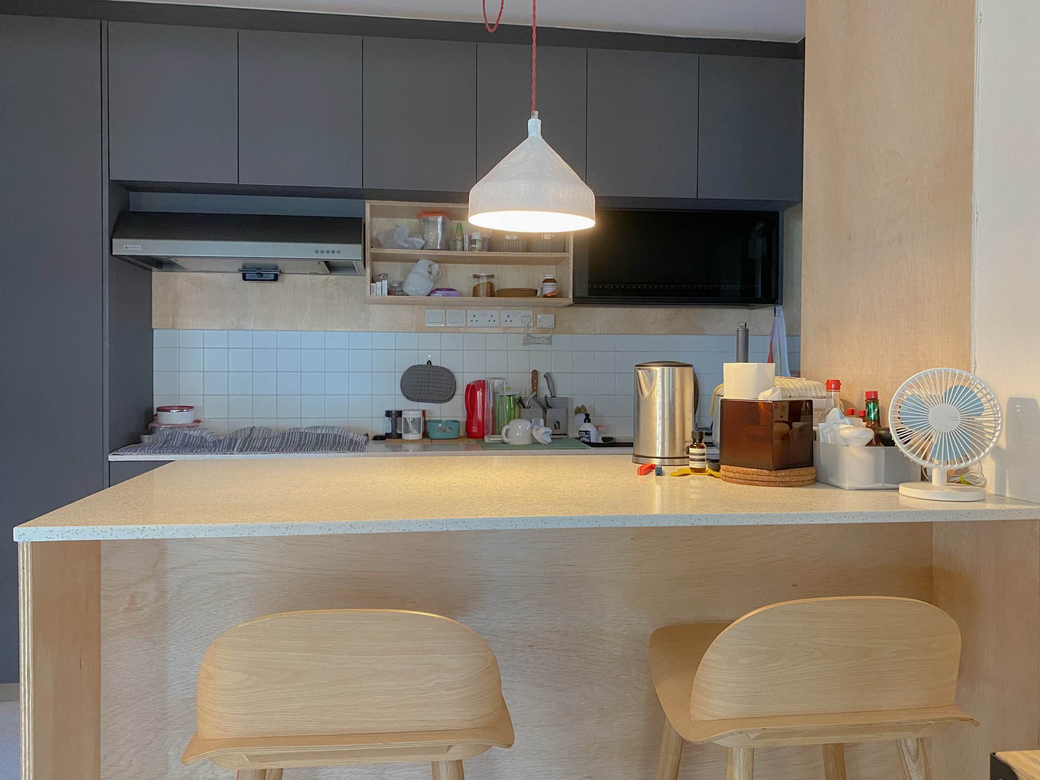The Eccentricity of an Artistic Couple’s Apartment - Modern kitchen with grey cabinets, white tiled backsplash, stainless
