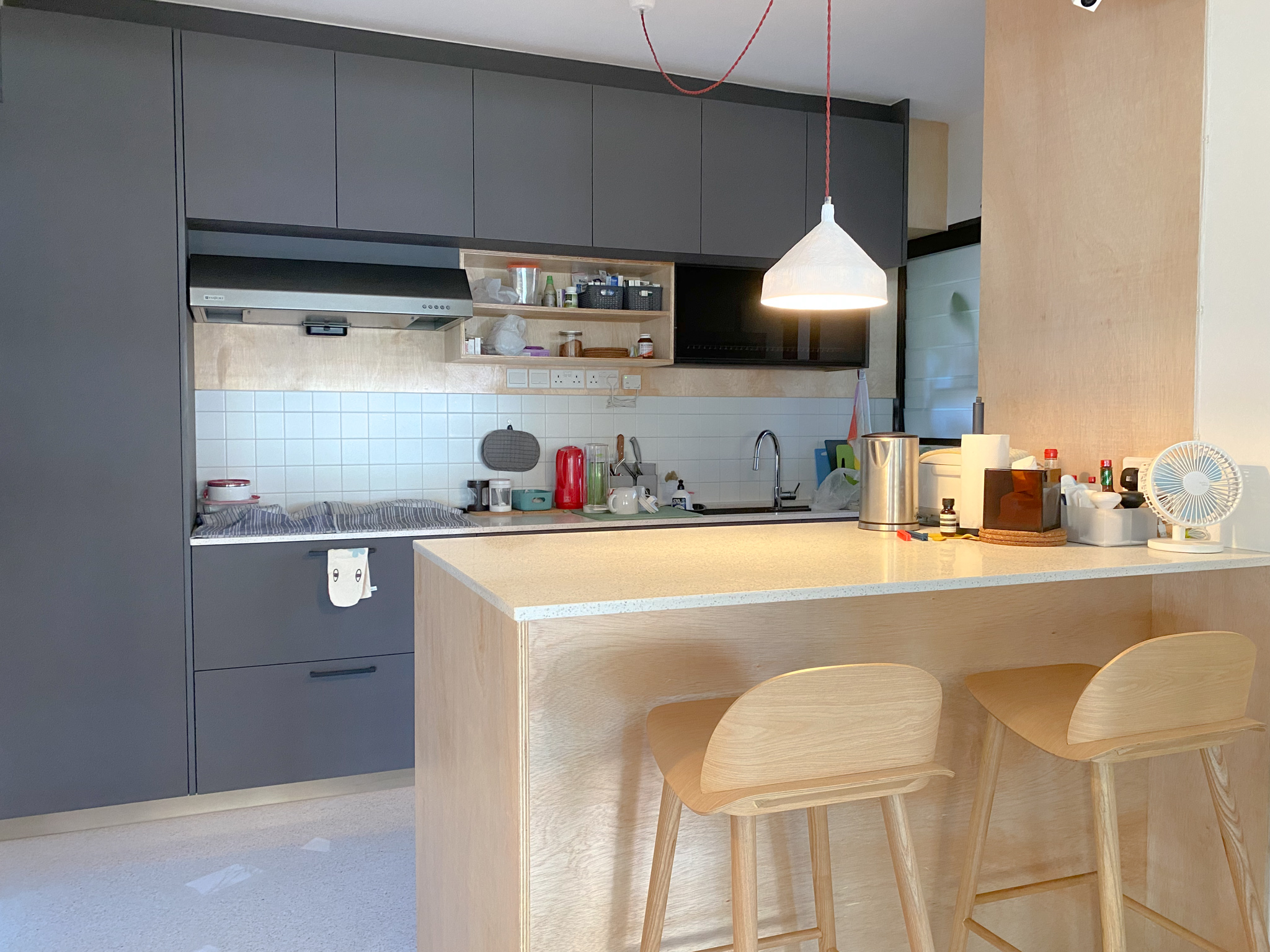 The Eccentricity of an Artistic Couple’s Apartment - Gray kitchen cabinets, white tiled backsplash, wooden countertop