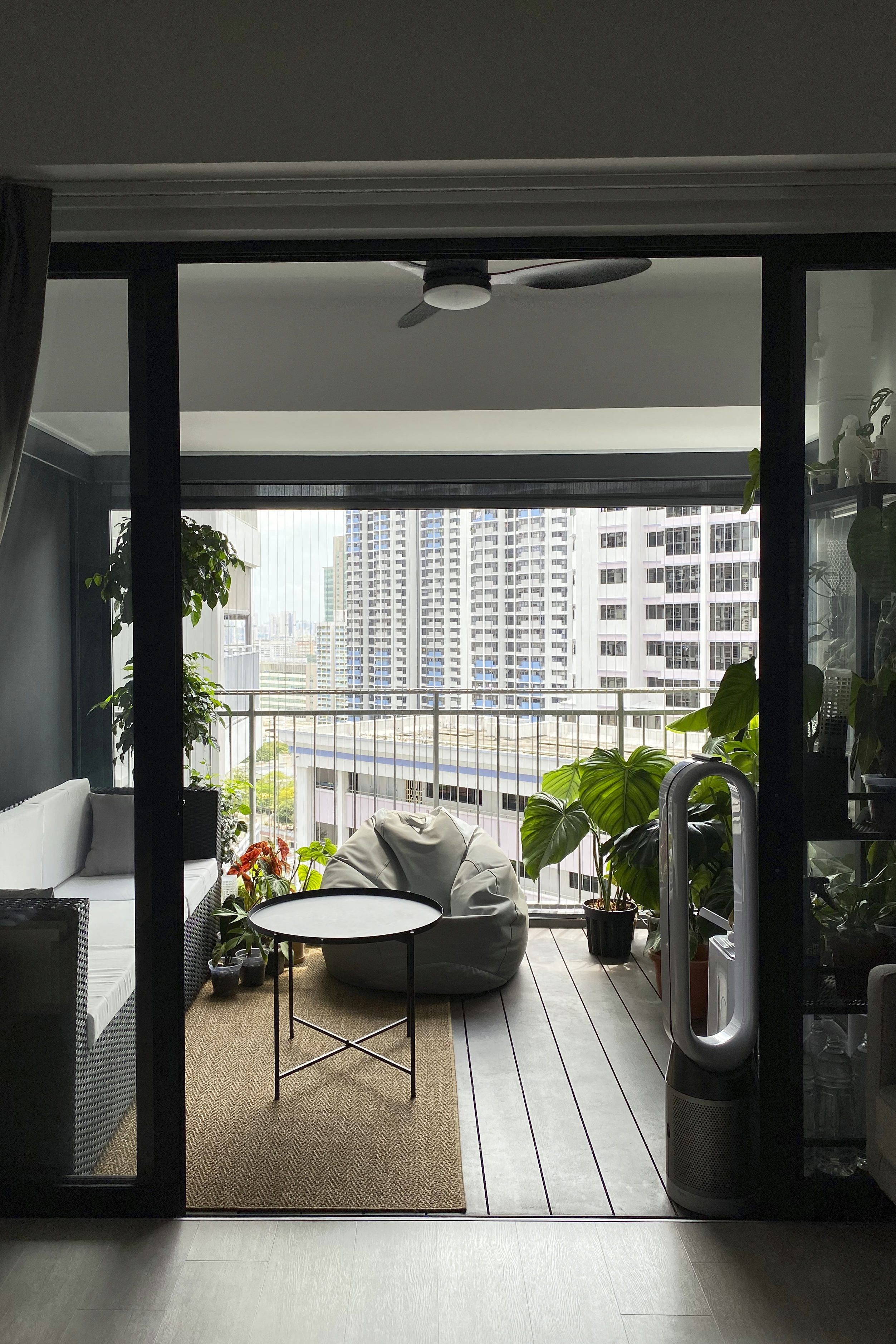 A Minimalist Apartment with an Urban Jungle - Modern living room with glass doors, urban cityscape view, indoor plants, cozy