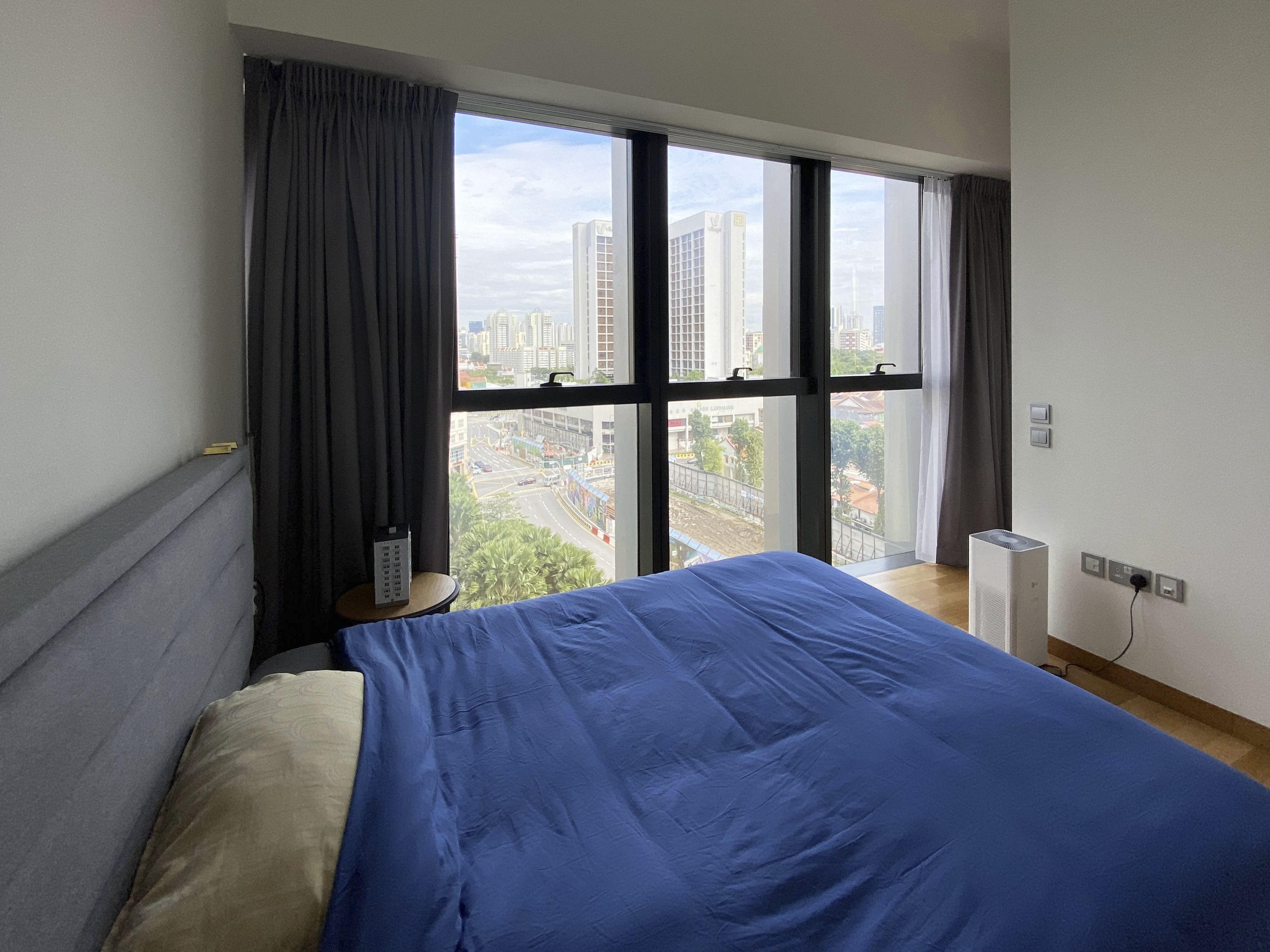 A Photographer's One-Room Studio Man Cave - Large comfortable bed with blue bedding, large window with dark curtains