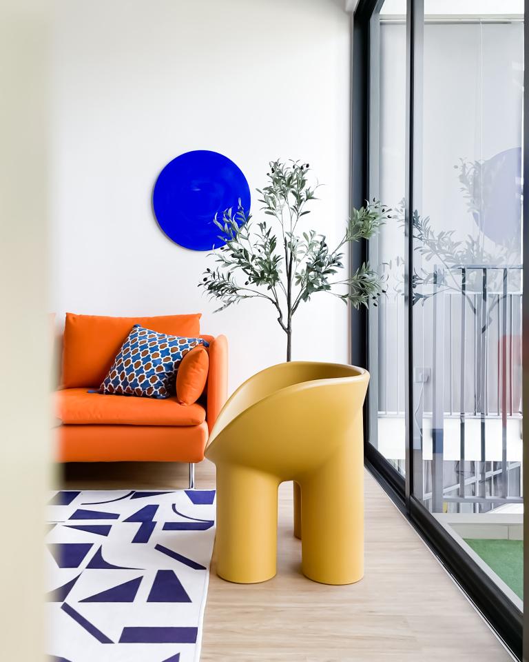 Bright colours are my jam - Modern living room, vibrant orange sofa, blue geometric pillows, abstract pattern rug, yellow