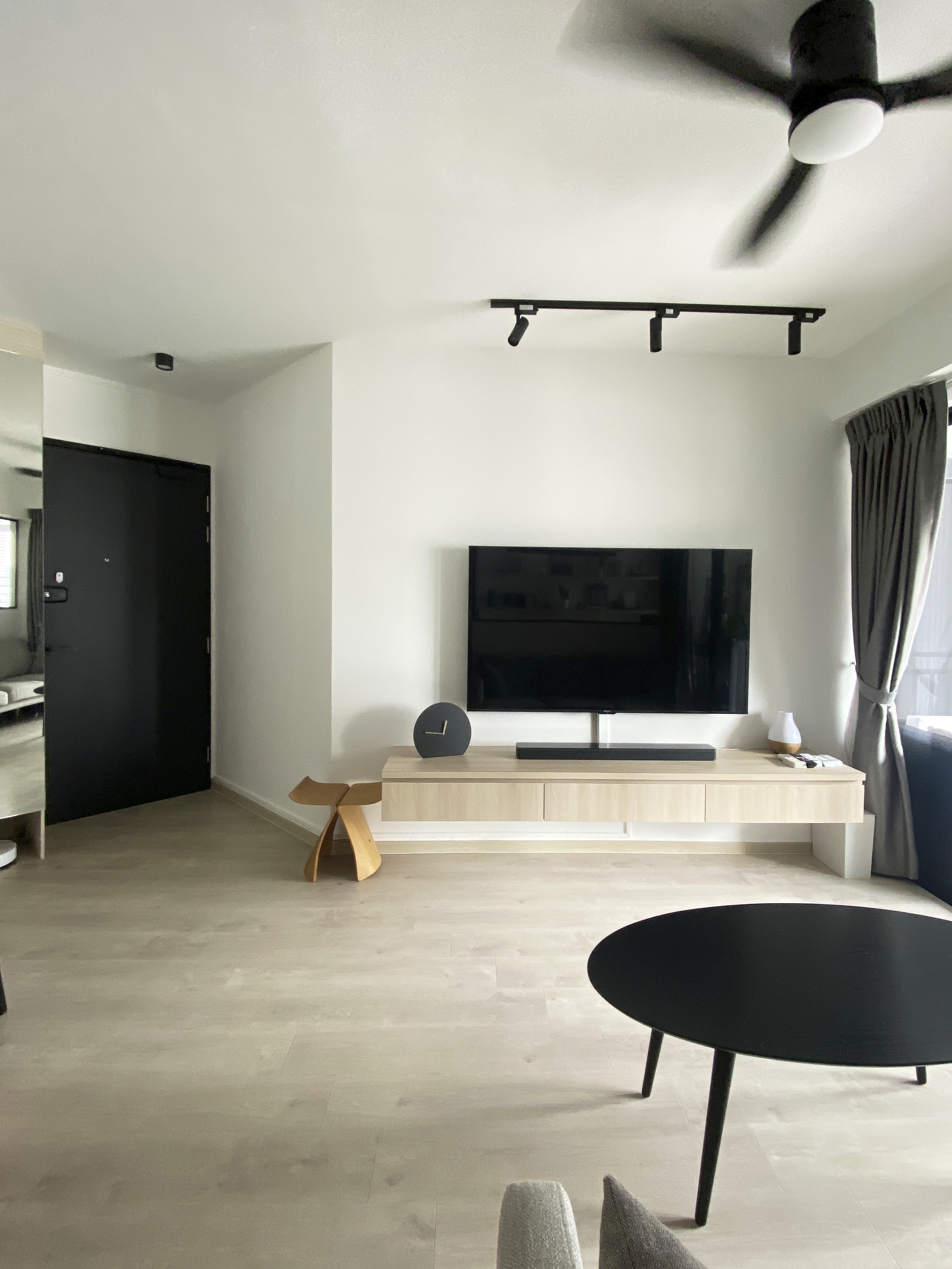 A Minimalist Apartment with an Urban Jungle - Modern minimalist living room, sleek black ceiling fan, light-colored wooden TV