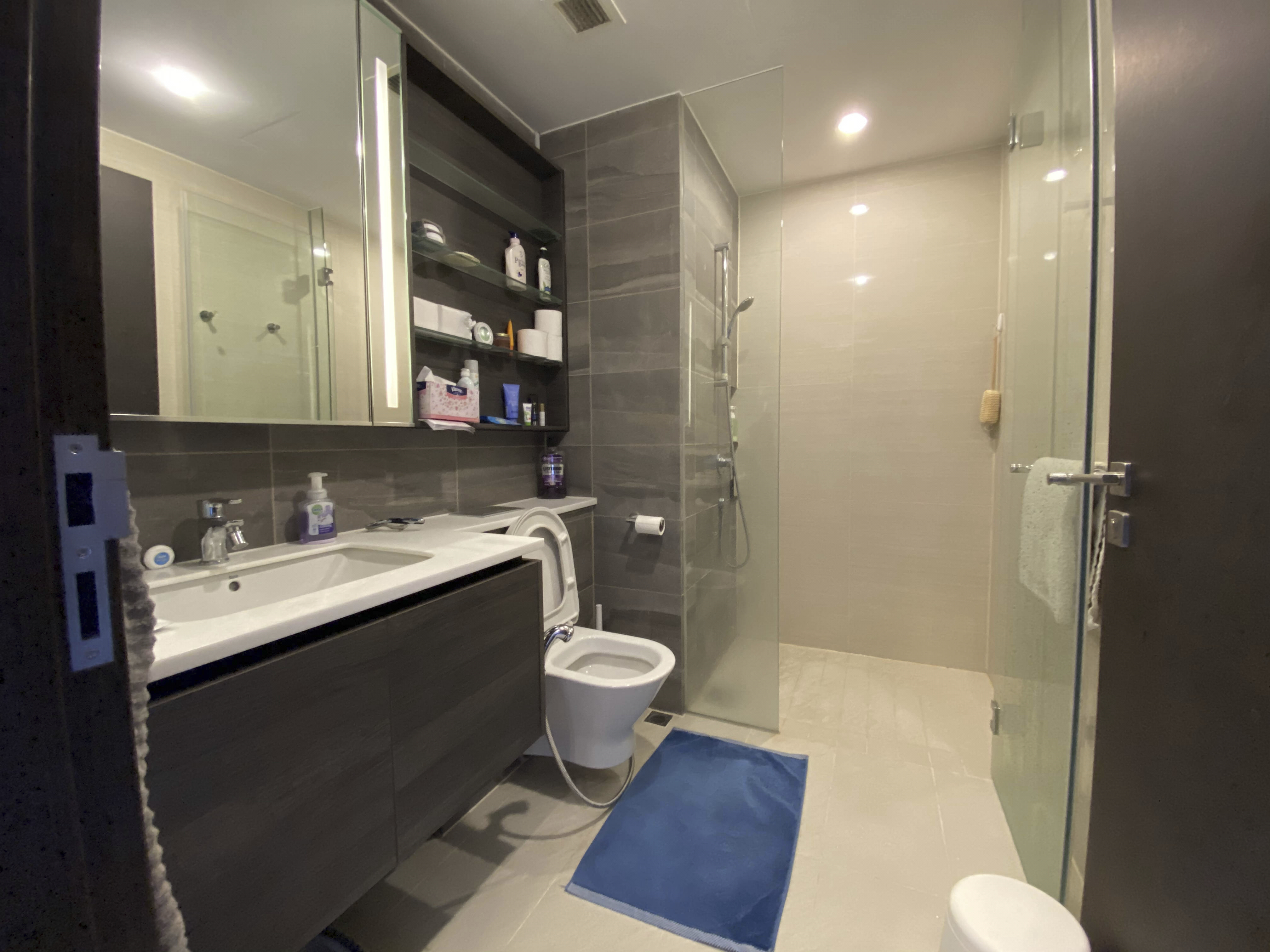 Our Smart Apartment That Might Be Smarter Than Us - Modern bathroom with sleek design, glass shower enclosure, white sink and