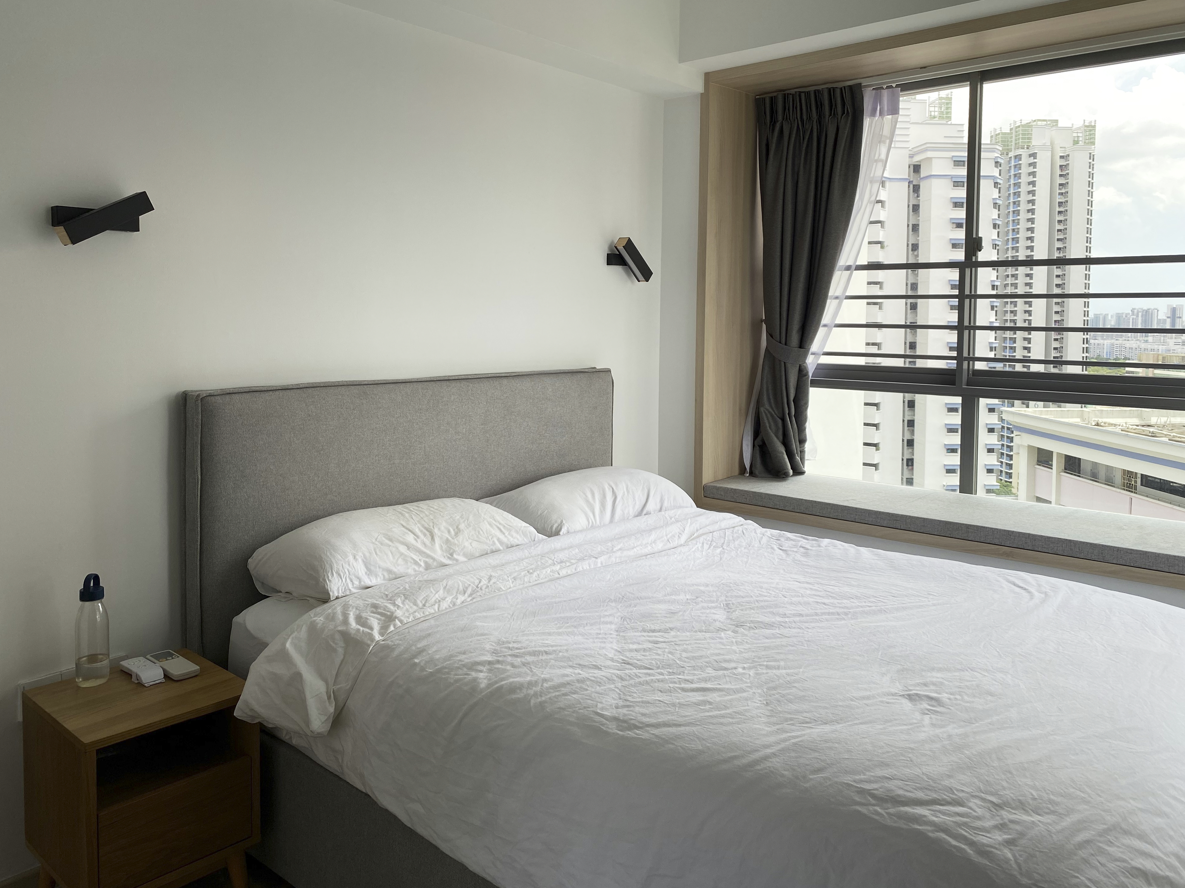 A Minimalist Apartment with an Urban Jungle - Modern minimalist bedroom, large window, cityscape view, gray upholstered
