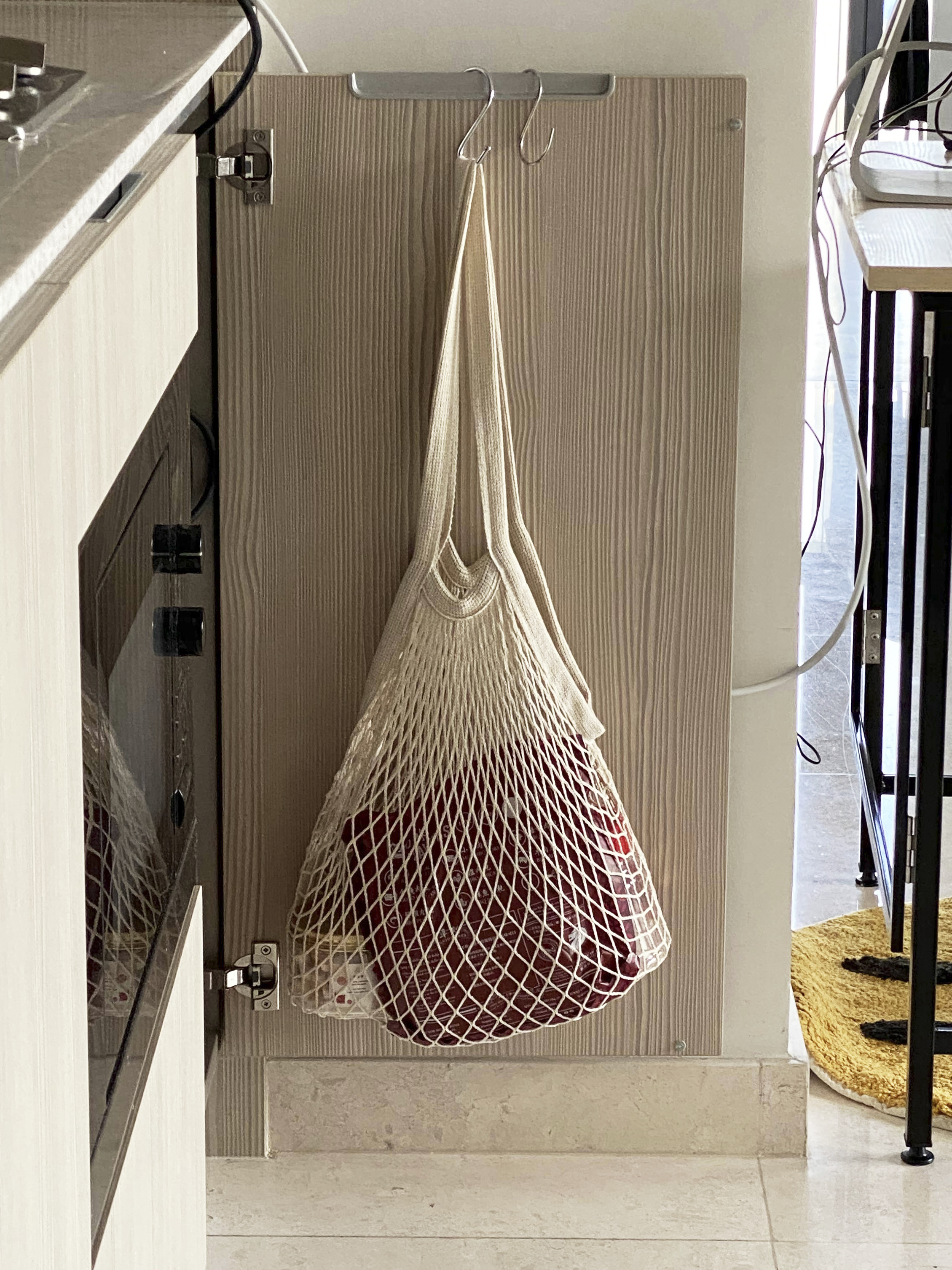 A Photographer's One-Room Studio Man Cave - Kitchen cabinet with beige countertop, hanging beige net bag, red fabric bag