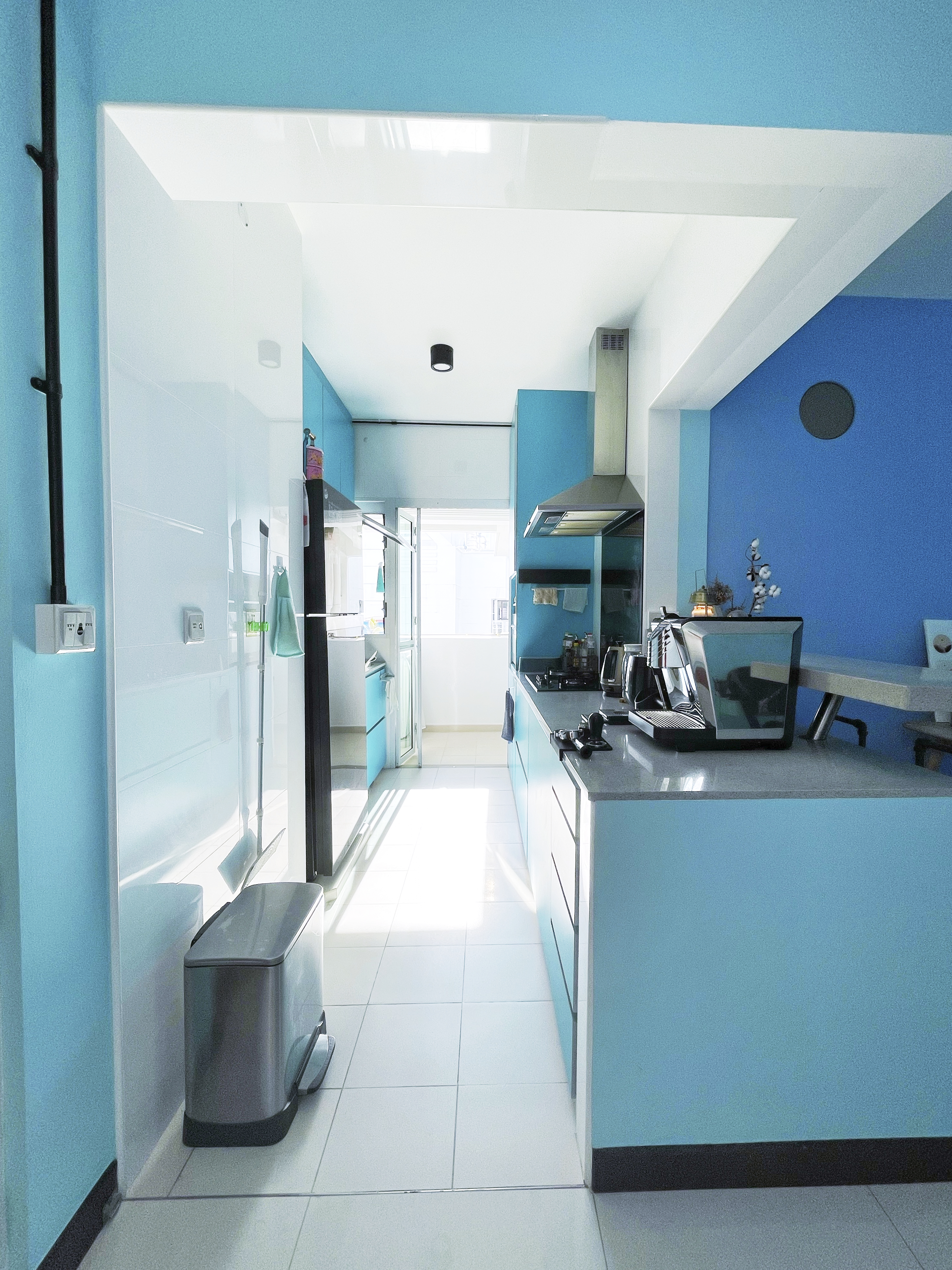 Our Colourful Personalities Imprinted On Our Apartment - Modern kitchen with blue walls, sleek appliances, bright lighting