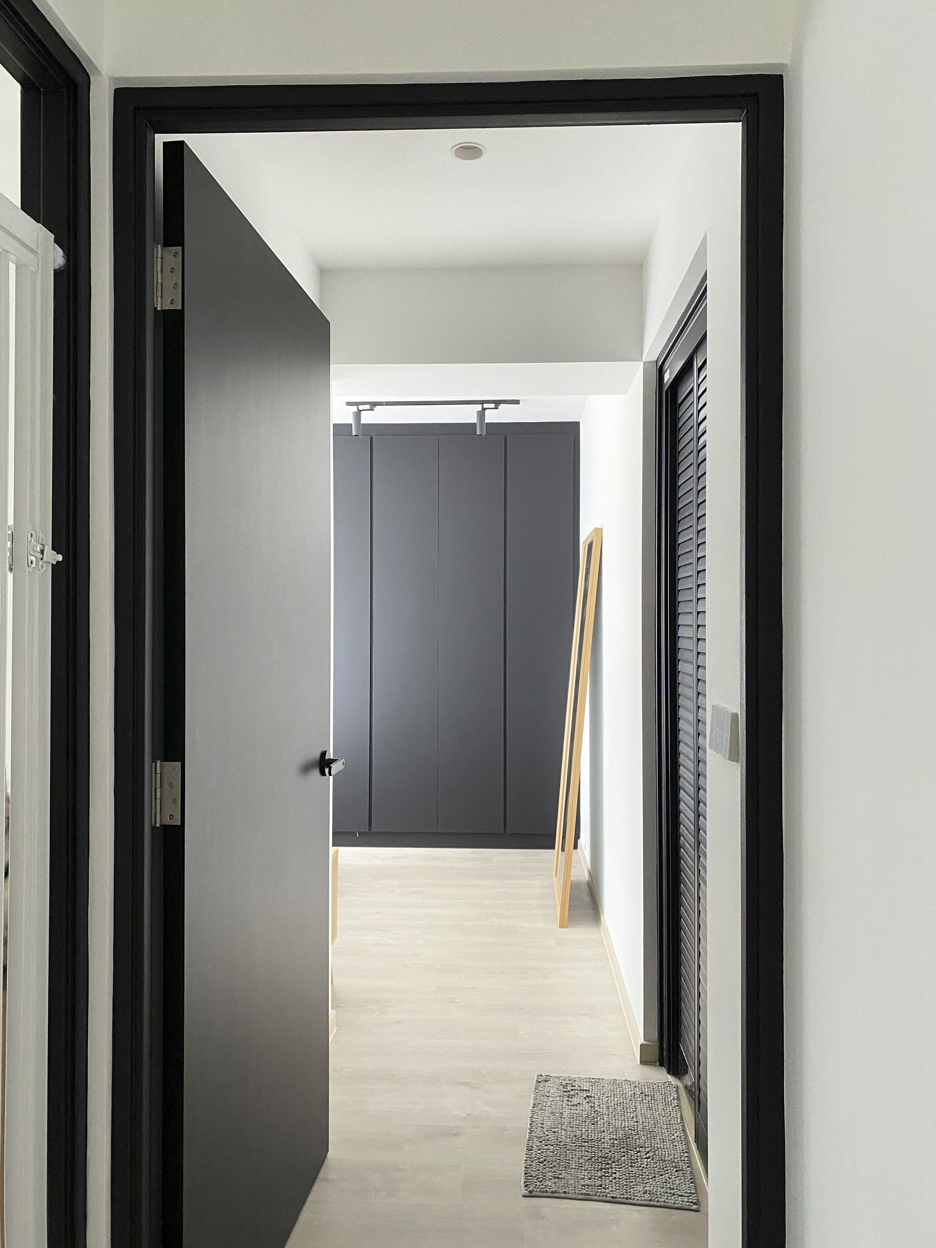 A Minimalist Apartment with an Urban Jungle - Modern minimalist interior, sleek black doors, open doorway, light-colored