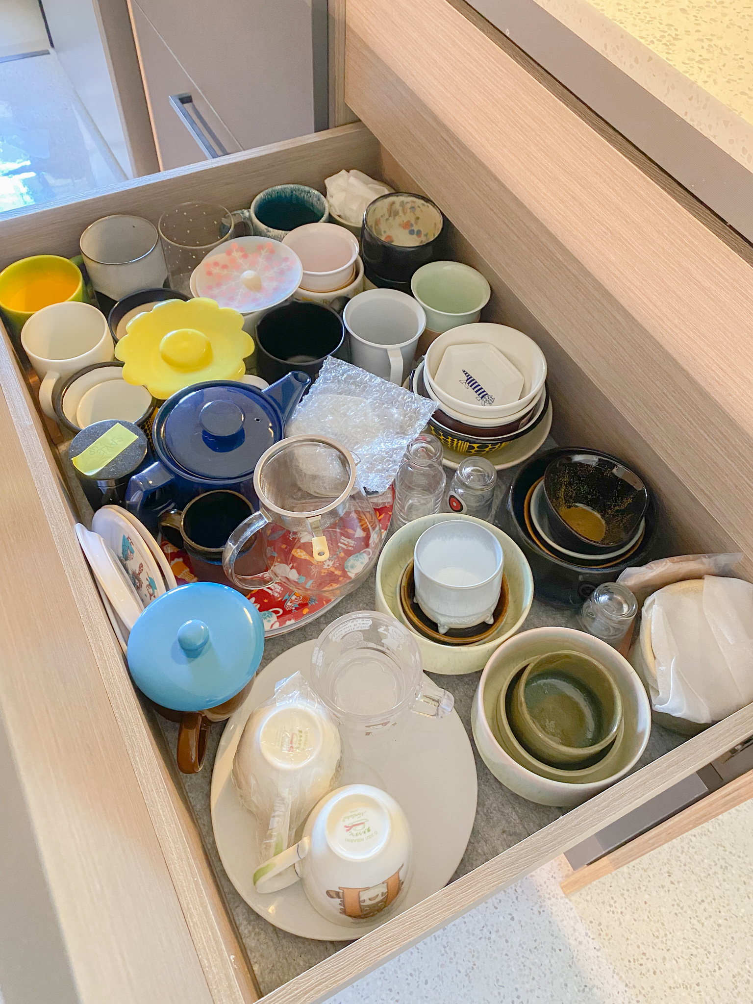 The Eccentricity of an Artistic Couple’s Apartment - Colorful ceramic dishes, wooden drawer, various bowls and cups, plastic