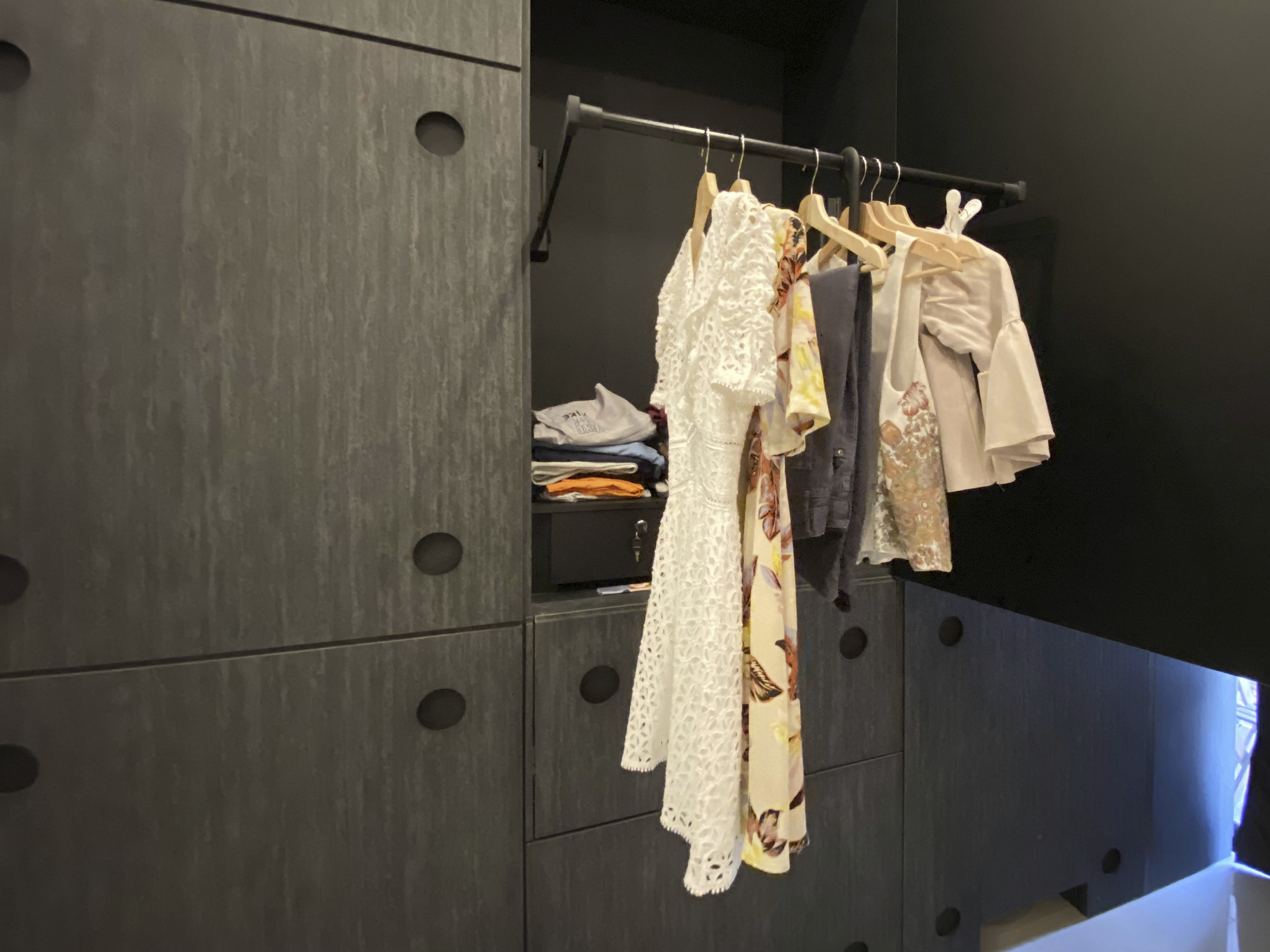 Our Smart Apartment That Might Be Smarter Than Us - Dark gray wardrobe with circular holes, hanging clothes, white lace