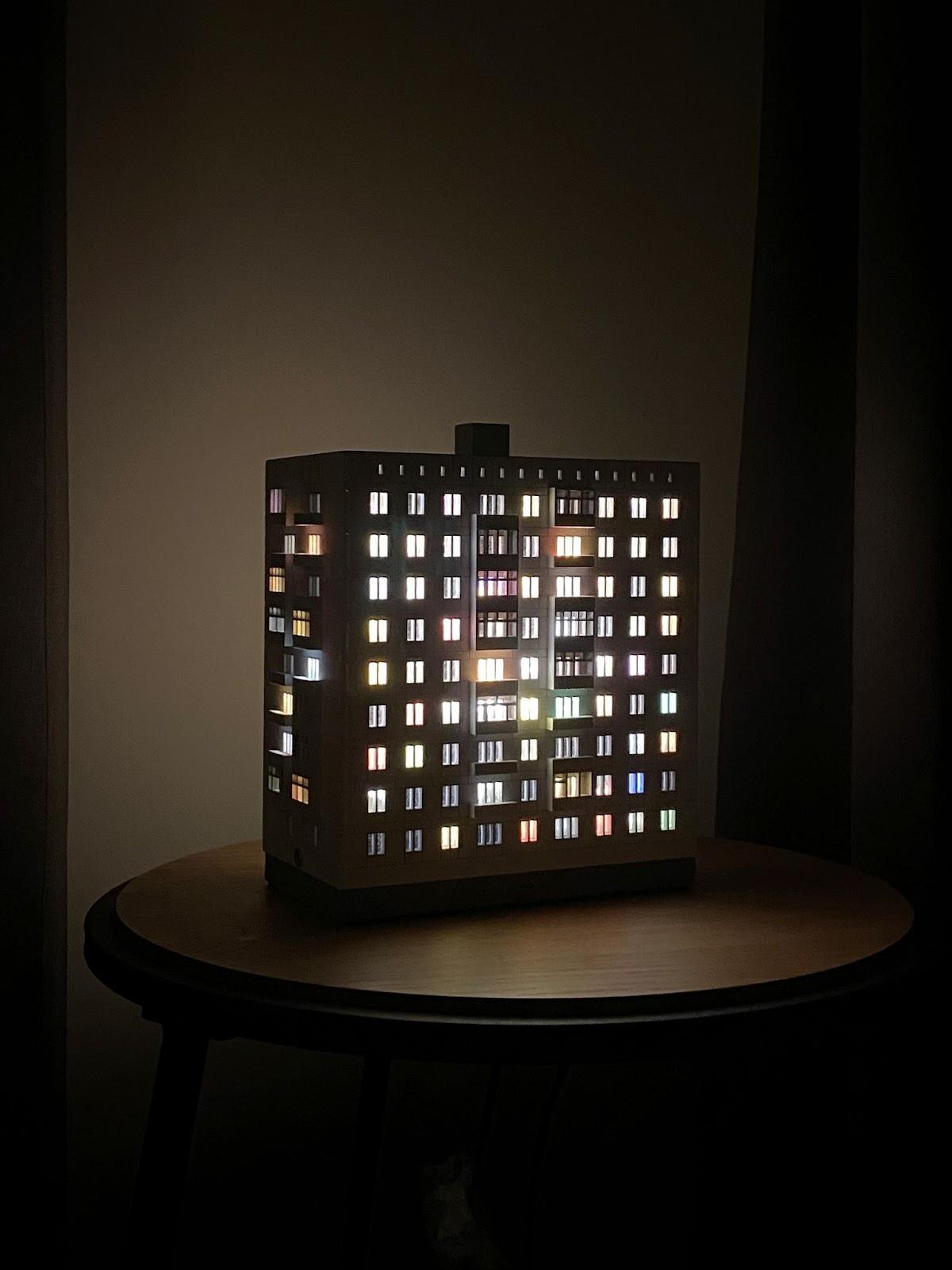 A Photographer's One-Room Studio Man Cave - Modern illuminated building model, multi-story apartment, glowing windows, warm