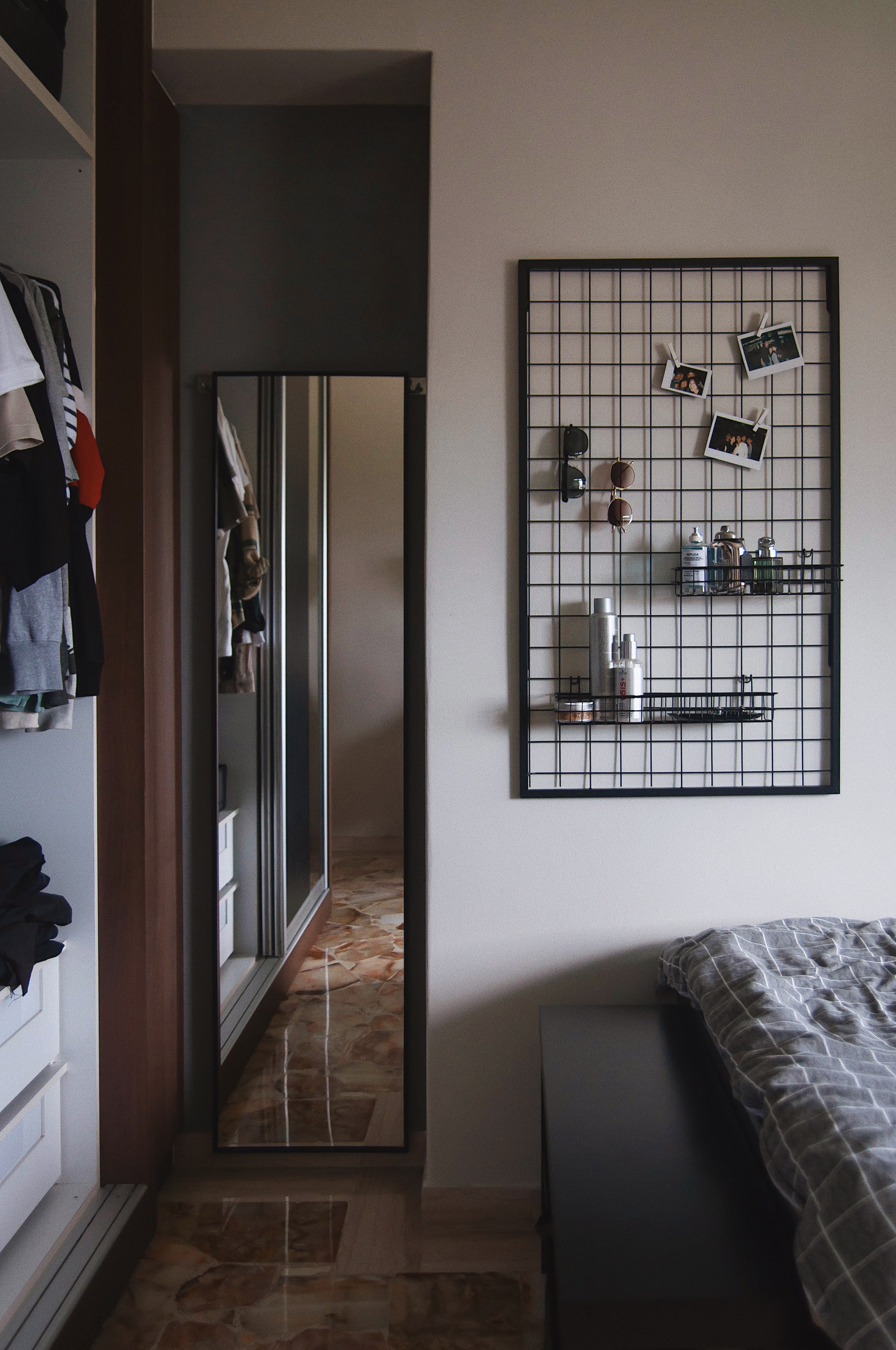 A Graphic Designer’s Humble Abode - Modern bedroom interior, mirror, wardrobe, open door, clothes hanging, black metal grid